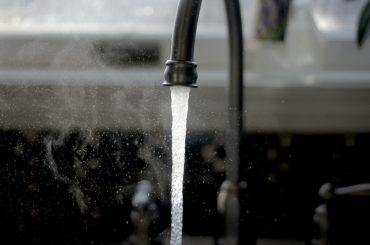 A close-up of a faucet with water running Description automatically generated