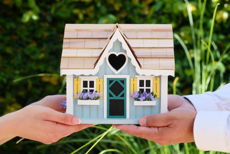 Free People Holding Miniature Wooden House Stock Photo