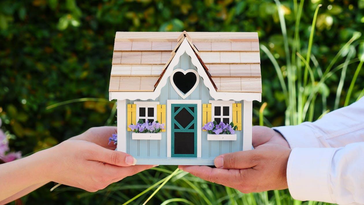Free People Holding Miniature Wooden House Stock Photo